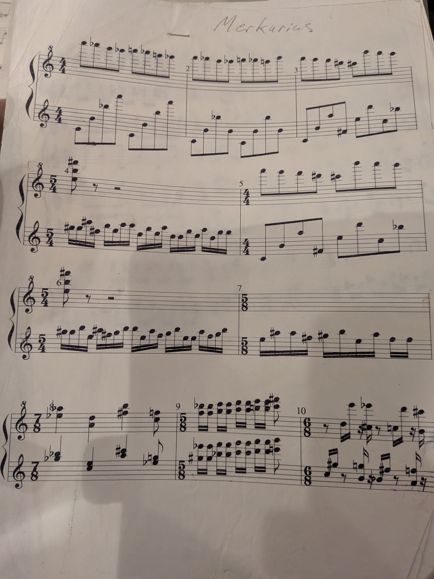 Photograph of the first page of the printed score of Merkurius, with the title handwritten at the top: two piano staves, bars 1 to 10, with wide leaps between the hands and changing time signatures.